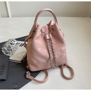 Detail shot of a pink bucket backpack with silver chain drawstring and top handle