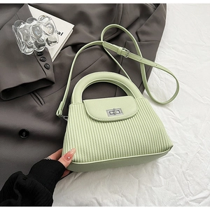 Detail of light green pleated handbag with silver twist lock and semi-circular handle