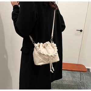 Dettaglio della borsa a secchiello trapuntata beige con manico intrecciato e metallo oro