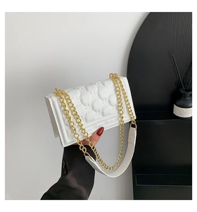 Detail of white quilted chain handbag with gold strap and elegant faux leather texture