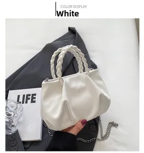 Detail of white pleated cloud bag featuring woven handles and silver chain strap