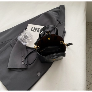Detail view of black lychee grain leather bucket bag with vintage gold hardware and inner pouch