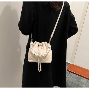 Dettaglio di una borsa a secchiello trapuntata beige con coulisse e manico intrecciato
