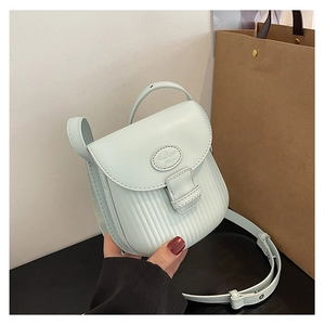 Detail of mint green crossbody bag featuring vertical embossed texture and flap closure