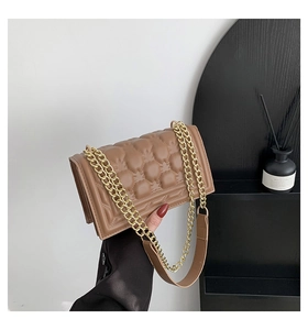Macro shot of brown quilted leather texture and gold chain strap on the handbag