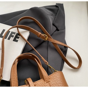 Detail of brown litchi pattern leather bucket bag with gold hardware and adjustable strap