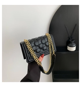 Detail view of the quilted bubble texture and gold metal chain on this black shoulder bag