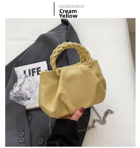 Detail of creamy yellow handbag showing pleated texture and woven handle on gray suit