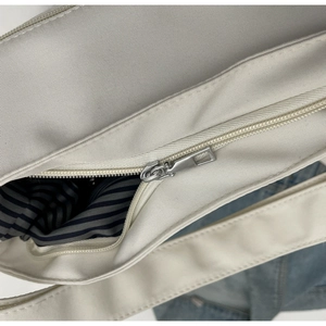 Detail view of the secure silver metal zipper closure on a cream canvas tote bag