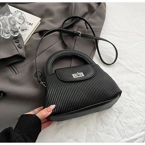 Detail of black quilted leather handbag with silver rotary buckle and pleated texture
