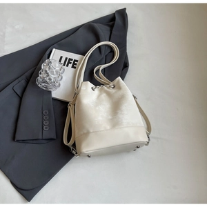 Detail view of cream bucket bag with silver chain drawstring and anti-wear metal feet