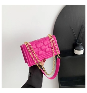 Detail of fuchsia quilted handbag with gold chain strap and elegant faux leather texture