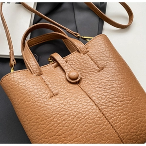 Close-up of caramel brown pebble leather texture and stitching on crossbody bucket bag