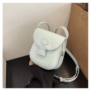 Detail of light green crossbody bag featuring vertical stripe texture and flap closure