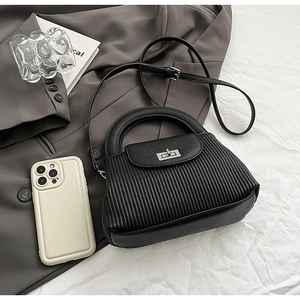 Detailed top view of black quilted crossbody bag with silver twist lock and smooth texture