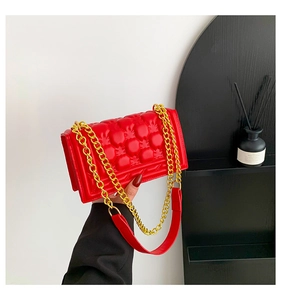 Detail of red quilted leather bag with pineapple texture and gold chain strap