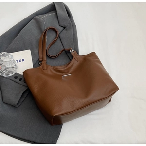 Detailed view of dark brown tote bag with silver metal bar and fine leather texture