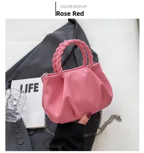 Detail view of rose red pleated cloud bag with braided handle and metal chain strap