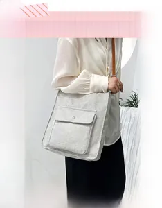 Detail of grey linen crossbody bag with large front pocket and brown leather strap