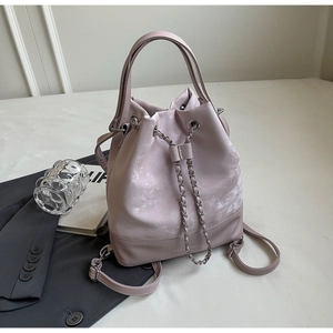 Close-up of pink bucket backpack with drawstring chain and embossed logo detail