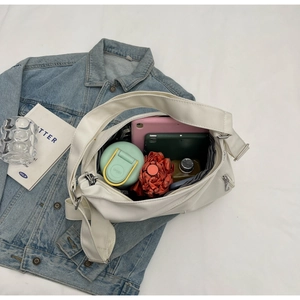 Detailed view of spacious interior of white crossbody bag holding tablet and umbrella