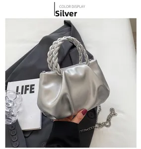 Detail of silver pleated cloud bag with braided handle and slim metal chain strap