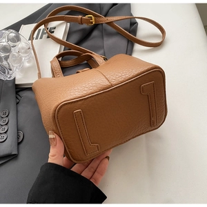 Detail view of brown lychee grain bucket bag with L-shaped bottom leather patches