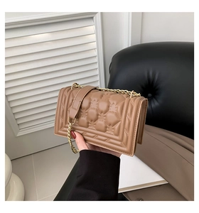 Detail of a brown quilted leather crossbody bag with gold chain strap and metal buckle