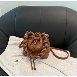 Dettaglio di una borsa a secchiello trapuntata marrone scuro con manico intrecciato