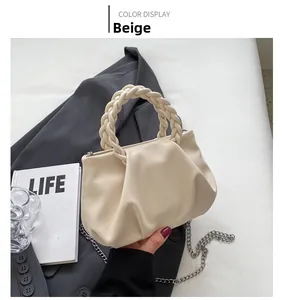 Detail of beige ruched handbag with woven handle and silver chain strap on gray blazer