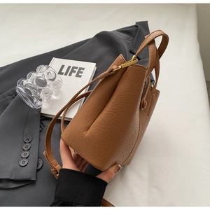 Detail of caramel leather bucket bag with pebble texture and sturdy shoulder strap