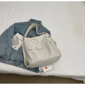 Detail of white large capacity tote bag featuring multi-pocket design on white bedding