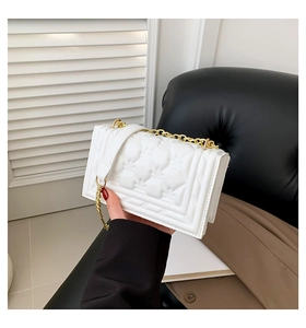 Detailed close-up of white quilted leather square bag with gold metal chain strap