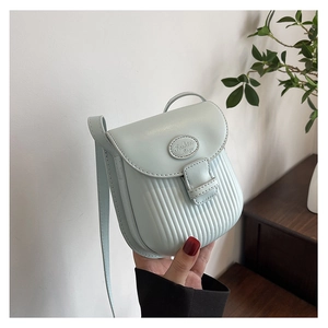 Detail of light blue crossbody bag with vertical striped texture and fashion tag