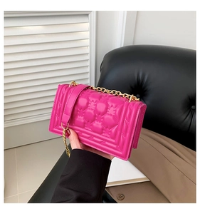 Detail of rose red quilted handbag with crown pattern stitching and gold chain