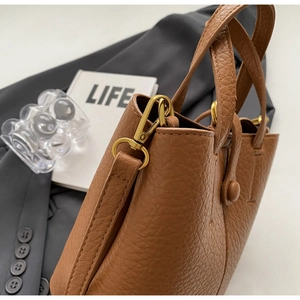 Close-up of brown litchi pattern bucket bag featuring golden metal hardware and lobster clasp