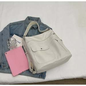 Detail of off-white multi-pocket tote bag with wide canvas strap on a white background