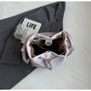 Detail shot of pink bucket bag with silver chain strap and striped interior lining