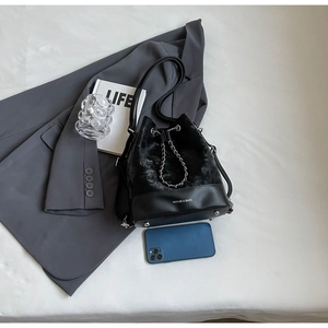 Close-up of plush bucket bag featuring silver drawstring chain and premium leather base