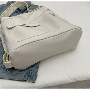 Detailed top view of a cream multi-pocket tote bag with adjustable woven shoulder strap