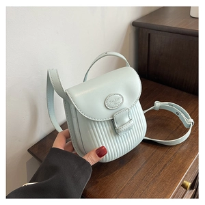 Detail of mint green crossbody bag with vertical striped texture and fashion logo