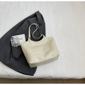 Close-up of cream white leather tote bag with lychee texture on neutral minimalist background