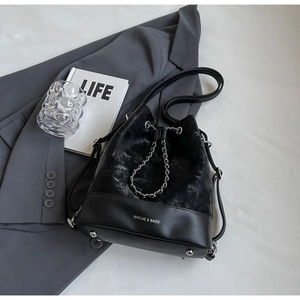Detail of black drawstring bucket bag with gold chain and polished metal studs