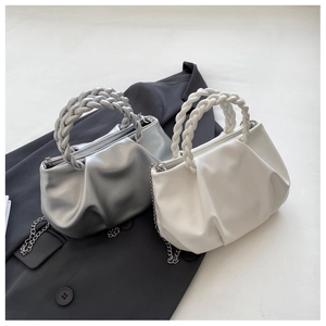 Detail view of white and silver pleated cloud bags with woven handles and metal chains