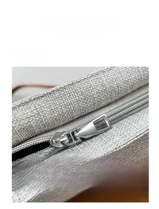 Detailed macro view of the light grey linen fabric texture and metal zipper closure