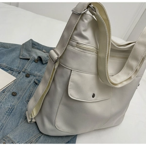 Close-up of beige PU leather tote bag with functional pockets and wide fabric strap