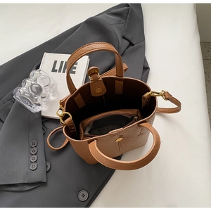 Brown bucket bag detail showing the interior space and matching zipper storage pouch