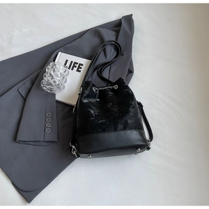 Macro shot of black velvet and matte leather bucket bag with silver chain and drawstring
