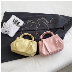 Detail view of ruched cloud bags in yellow and pink with woven handles and silver chains