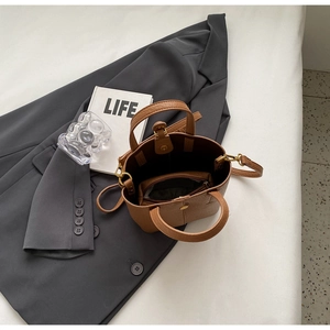 Top view of brown leather bucket bag with removable strap and golden hardware